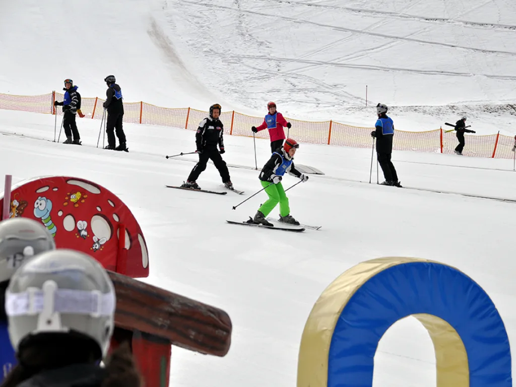 Skifahrende üben am Parcours mit bunten Elementen.